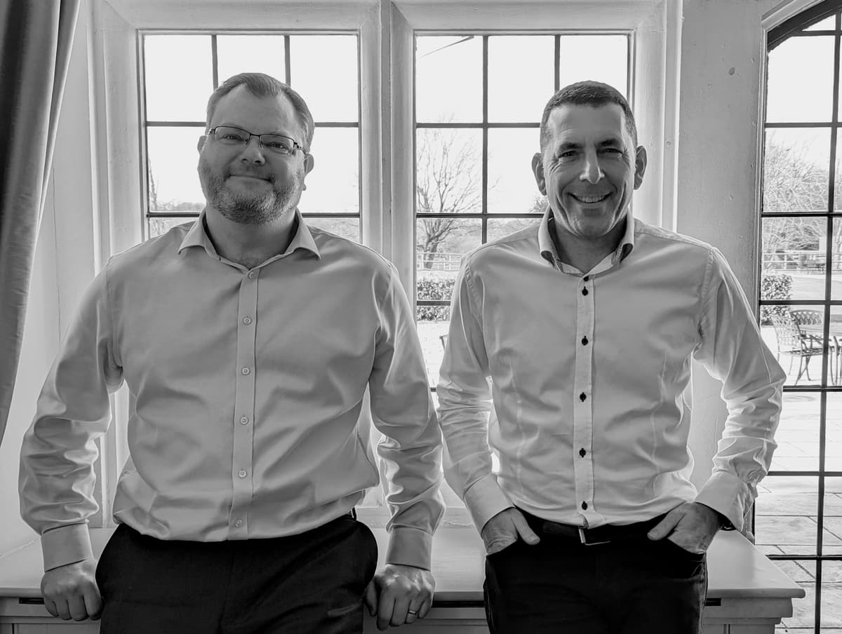 Spencer & Tim standing next to a window